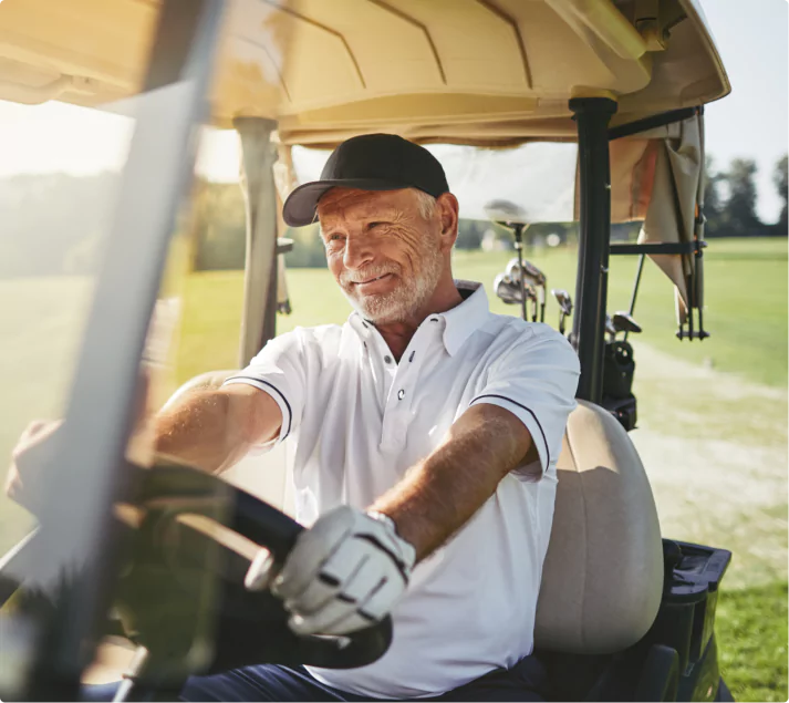 Adulto mayor sonriendo mientras maneja carrito golf