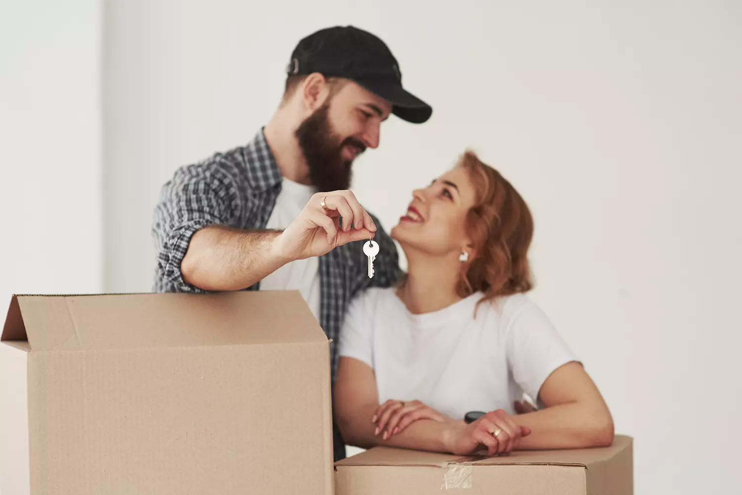 Pareja con cajas de mudanza y con las llaves de su nueva casa