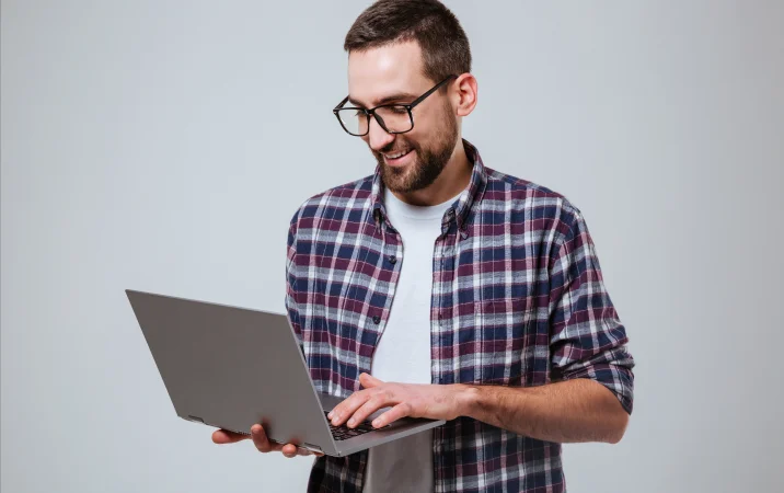 Hombre sonriente cargando su laptop