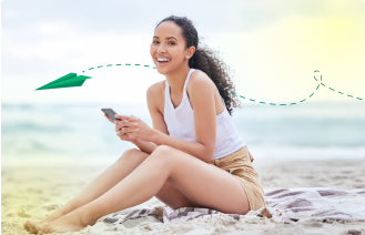 Mujer sonriente viendo la app de Bancanet en su celular en la playa Mujer sonriente viendo la app de Bancanet en su celular en la playa