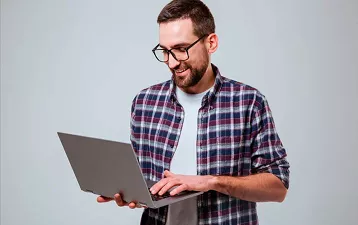 Hombre sonriente cargando su laptop