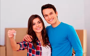 Pareja joven sonriente con llaves de su nueva casa