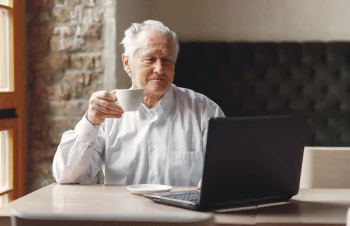 Hombre adulto usando computadora portátil y tomando una tasa de café