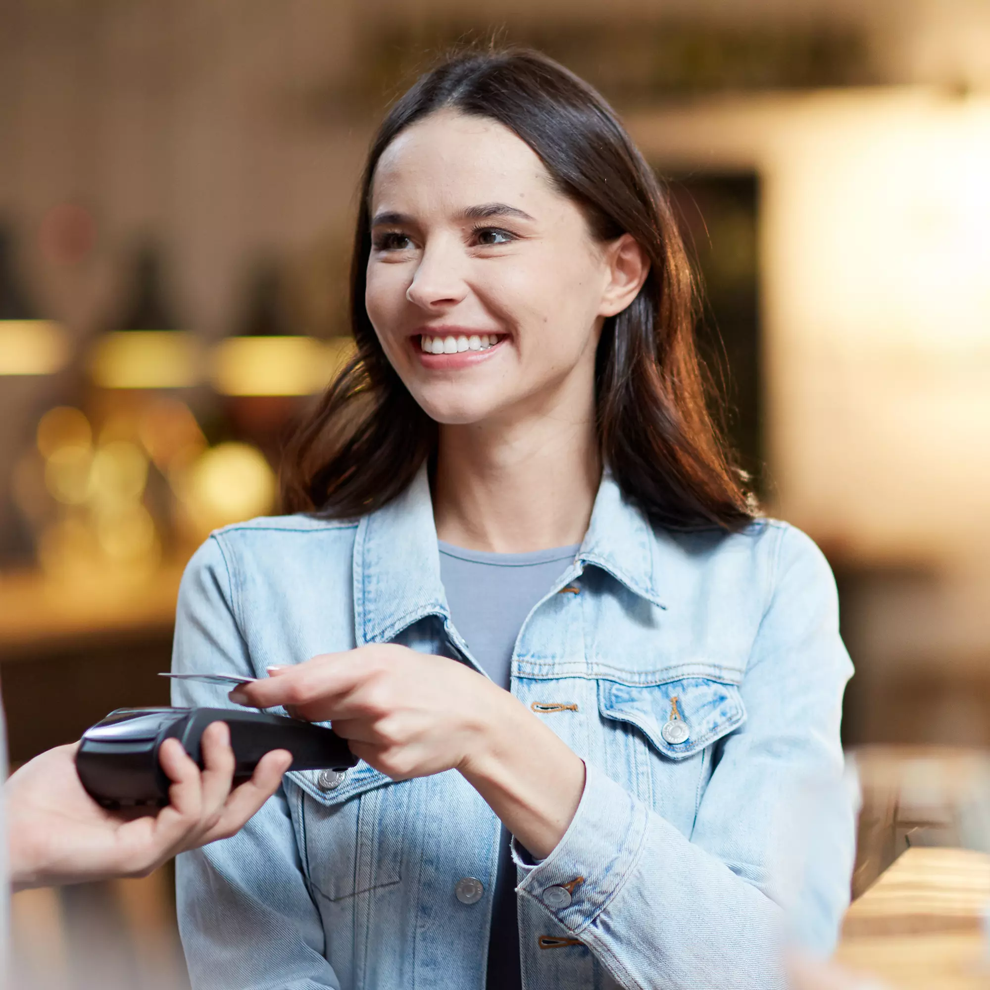 Mujer joven pagando en un negocio con su tarjeta Mujer joven pagando en un negocio con su tarjeta