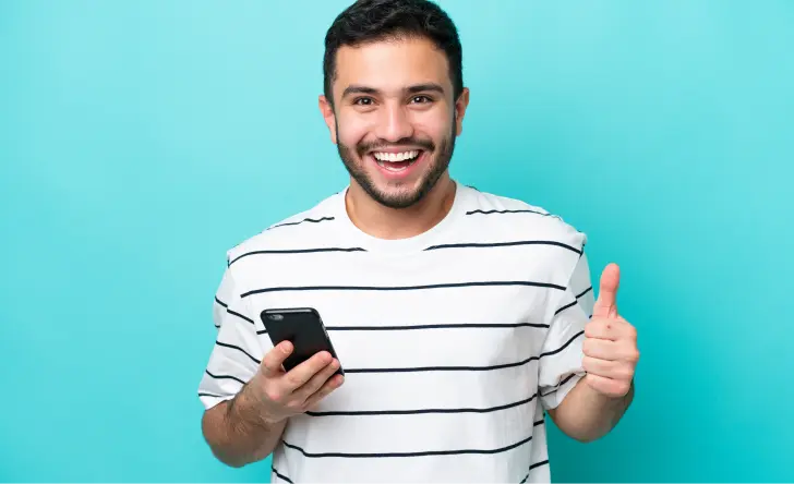 Hombre joven sonriente con celular en mano