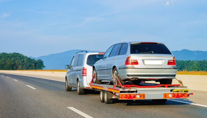 Auto en carretera siendo remolcado por una grúa durante el día.