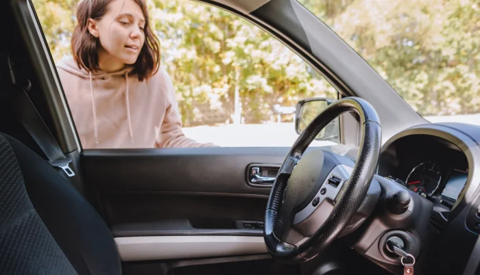 Mujer deja la llave dentro del automóvil y observa su interior por la ventana.