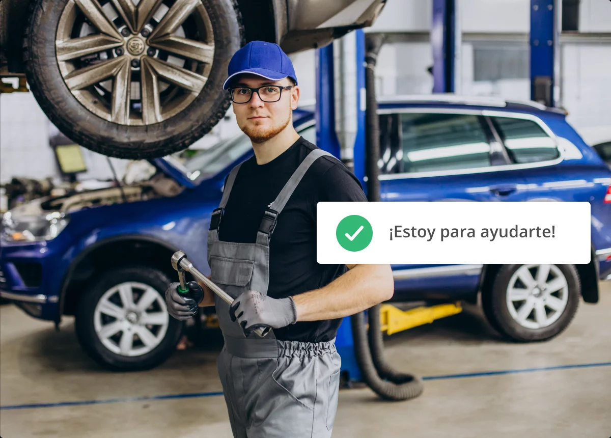 Mecánico con herramientas en un taller con camioneta azul de fondo.