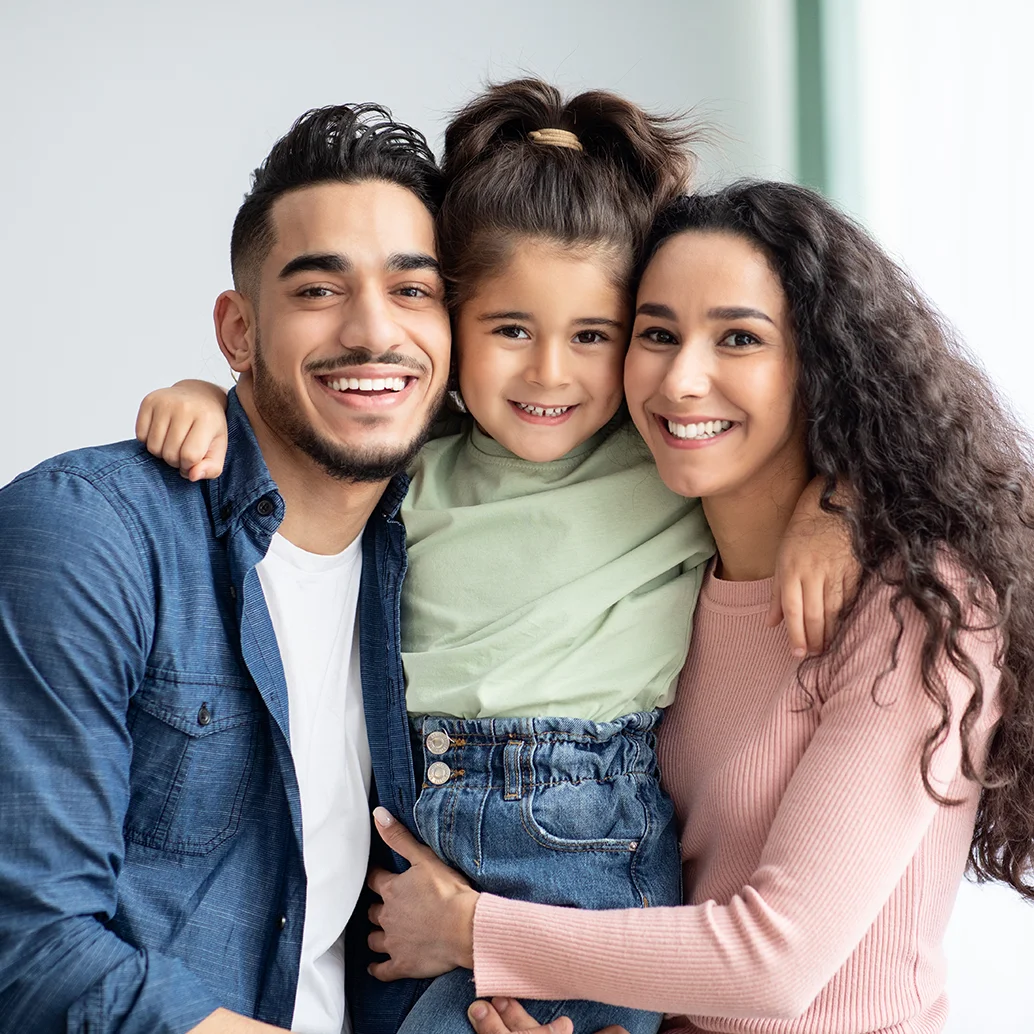 Familia de tres con hija, sonriendo abrazados frente a la cámara. Familia de tres con hija, sonriendo abrazados frente a la cámara.