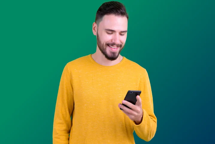 Hombre joven sonriente con celular en mano