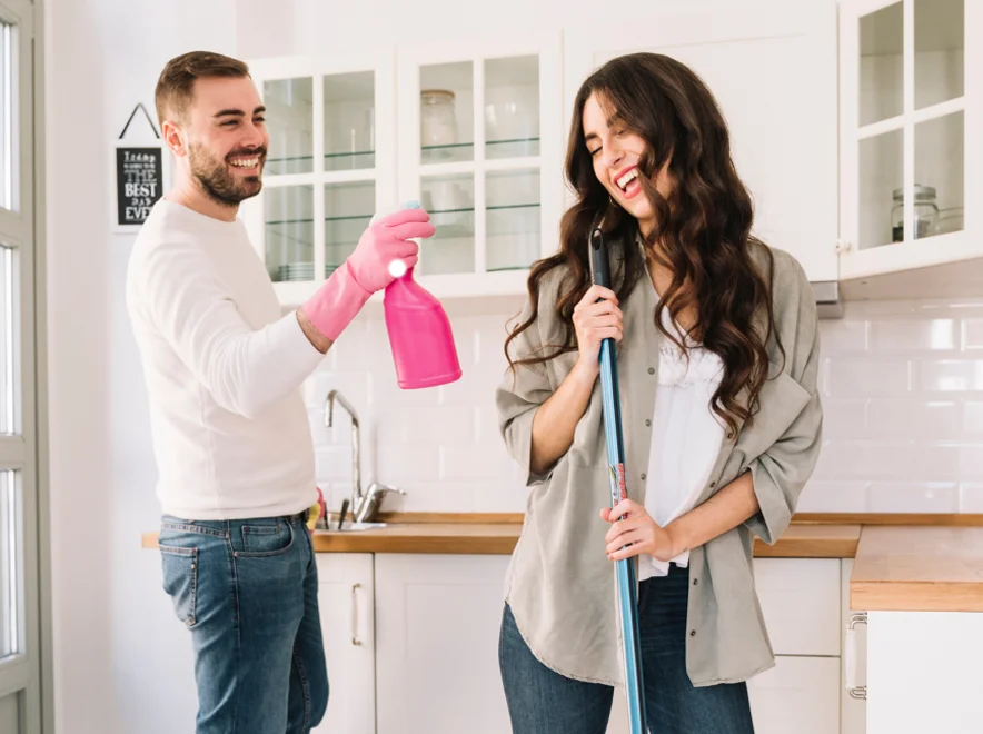 Pareja feliz limpiando la cocina de su casa.