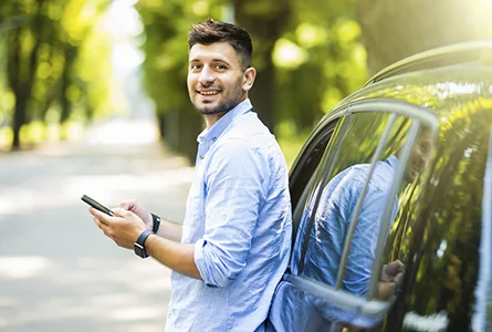 Hombre sonriente recostado en auto Hombre sonriente recostado en auto